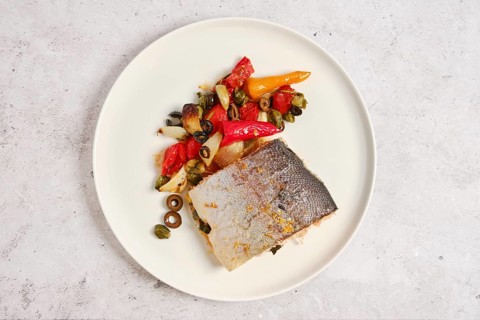 Piece of oven roasted sea trout with vegetables on a plate, top view
