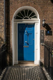 Blue front door in brick façade with chequered floor and wrought-iron fence, Holborn, London