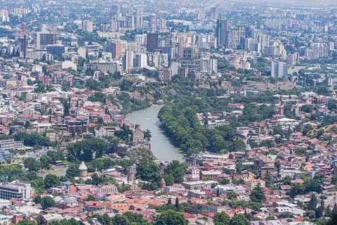 Aerial view of Tbilisi showcasing a blend of historic and modern architecture. The Kura River winds