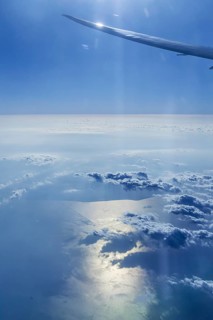 View of the Persian Gulf from the aeroplane window. Sun and clouds over the sea. Flight with the