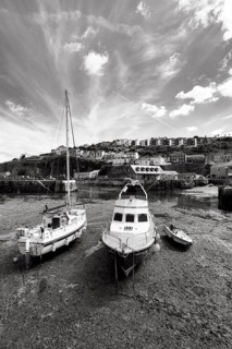 Fishing boats in tidal harbour, low tide, monochrome, Mevagissey, St Austell, Cornwall, England,