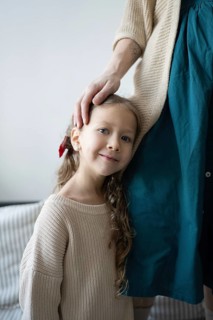A young child leans against an adult, feeling comforted and loved The adult's hand gently rests on