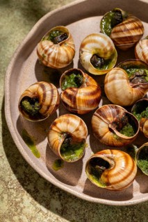 From above a delectable dish of baked escargots, generously topped with melted butter and fresh