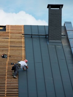 Building crew working on the roof sheeting in Lubin, Poland