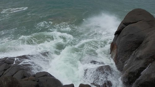 Strong waves break with spray over rocks on the coast, Sri Lanka