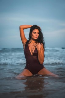 Caucasian brunette in maroon swimsuit, on the beach enjoying the holidays in the sea water on her