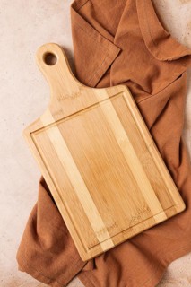 Cutting board, beige, unpainted, with a kitchen towel, on a beige background, top view