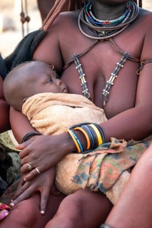 Himba woman holding a baby, traditional Himba village, Kaokoveld, Kunene, Namibia