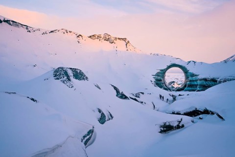 A naturally formed circular ice arch stands prominently amid the snow-covered landscape of Katla