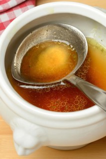 Bouillon, beef broth with ladle in bowl