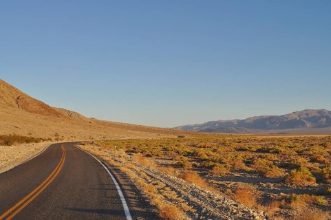 Lonely road through the desert in evening light with mountains in the background, Death Valley