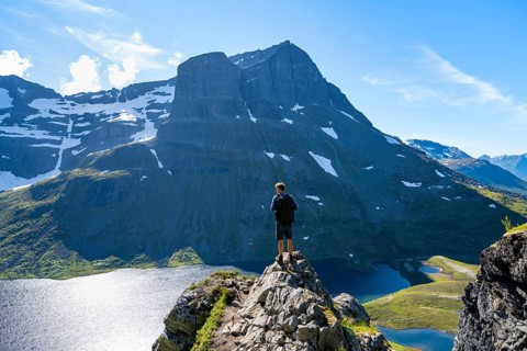 Hiker standing on a rock, view of mountain landscape and lake Giklingdalsvatnet, Flatvaddalen high