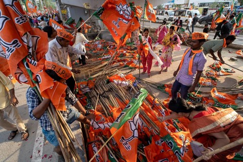 Supporters arrange flags of the Bharatiya Janata Party ahead of a public rally for the Assam