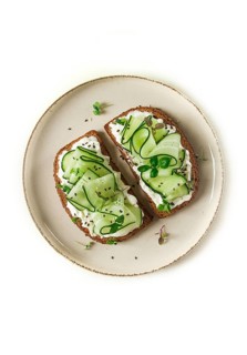 Breakfast, cereal bread sandwiches, cream cheese, sliced cucumber, with micro greenery on a light