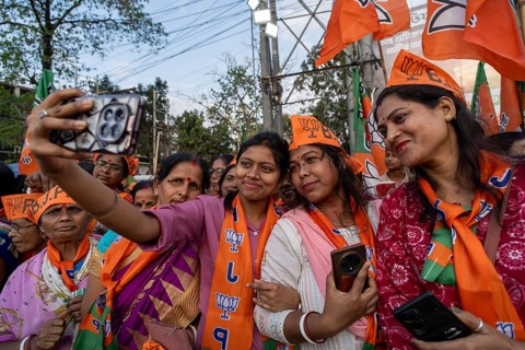 Supporters wearing scarves of the Bharatiya Janata Party take a selfie during a public rally ahead
