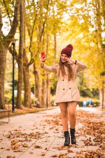 Portrait of a beautiful woman in autumn next to a forest in nature making a video call