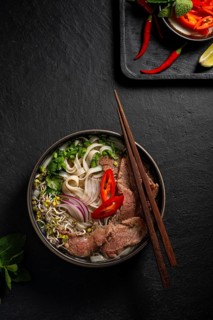 Top view of a delicious bowl of Vietnamese Beef Pho Noodle Soup, featuring tender slices of beef,