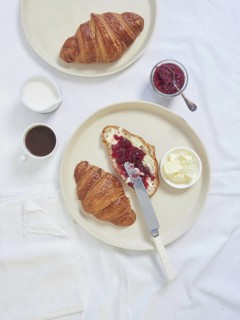 Continental breakfast served on white tablecloth croissants, butter, jam and cup of coffee