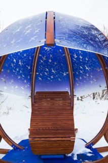 Interactive cocoon rocking chair made of curved wood and backlit blue tinted plexiglass panels
