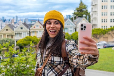 Happy young woman traveling, holding a smartphone and recording a selfie video with the iconic