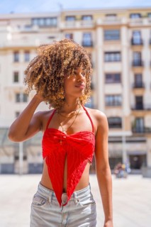 Vertical photo of a sensual latin young woman caressing her curly hair standing looking aside in