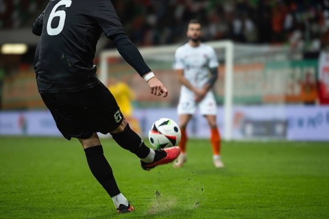 Soccer player kicks the ball during football match. Opponent player in the wall