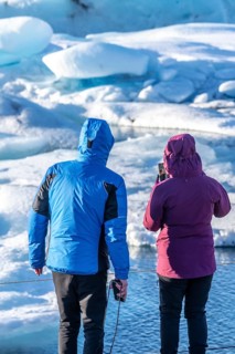 A couple looking at floating icebergs in the Jokulsarlon glacier lagoon in Iceland