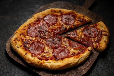 A mouthwatering homemade pepperoni pizza with melted cheese and a crispy crust sits on a wooden