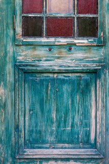 Weathered turquoise wooden door with small colourful windows, rustic and antique look, Turkey