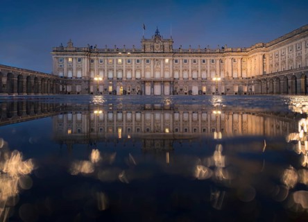 Stunning evening view of the Royal Palace of Madrid with illuminated windows, elegantly reflected