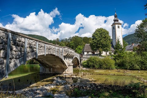 A picturesque view of the historic stone bridge and the Church of St. John the Baptist with its