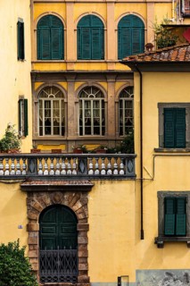Arched entrance gate and arched windows with green shutters in a pastel-coloured façade, historic,