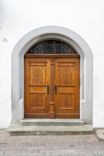 Frontal view of a historic portal on an old town house façade with a two-wing wooden door showing