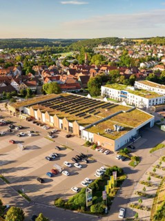 Urban aerial view of a large building with solar cells on the roof and an adjacent car park, Weil