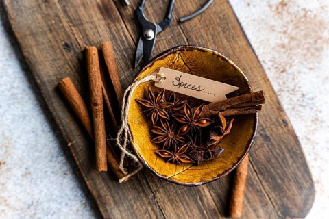 Top view of a rustic, textured wooden surface featuring star anise and cinnamon sticks arranged in