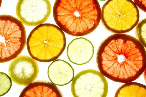 An array of colorful citrus slices, including orange, grapefruit, and lime, illuminated against a