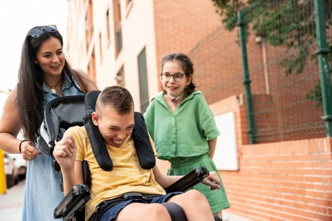 Family enjoys outdoor time, featuring a girl with tracheostomy and a boy with cerebral palsy.