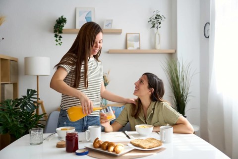 A lesbian couple shares a warm, intimate breakfast at home Natural light fills the room,