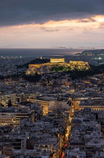 View over the sea of houses of Athens, illuminated Parthenon temple on the Acropolis, from Mount