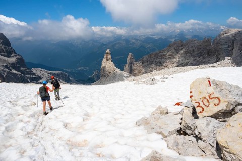 Hikers on hiking trail 305 cross a snowfield, Brenta Mountains, Parco Naturale Brenta-Adamello,