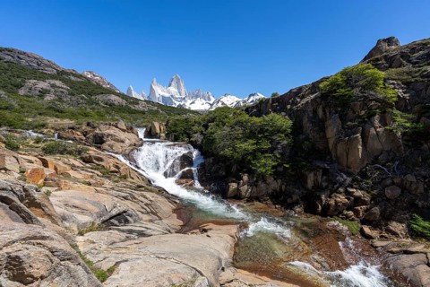 Chorrillo del Salto waterfall flows over rock steps, in the background the Fitz Roy mountain range