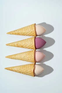 A whimsical arrangement of cosmetic sponges placed in waffle cones, resembling ice cream The pastel