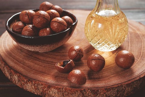 Bottle of macadamia oil, on a wooden board, with macadamia nuts, wooden background, selective