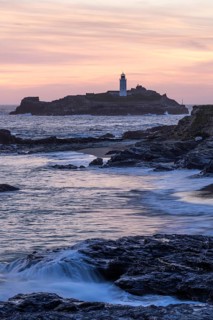 Godrevy Lighthouse, the lighthouse of Godrevy on Godrevy Island in the sea. Rocks in the foreground