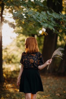 A woman stands amidst the vibrant autumn foliage of a Quebec forest, bathed in the warm glow of the