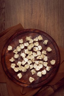 Traditional Turkish dumplings, raw, on a cutting board, top view, no people