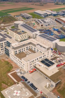 Aerial view of a modern industrial park with solar panels on building roofs, opening hospital,