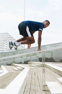 A black male athlete demonstrates agility and strength as he trains outdoors, showcasing dynamic