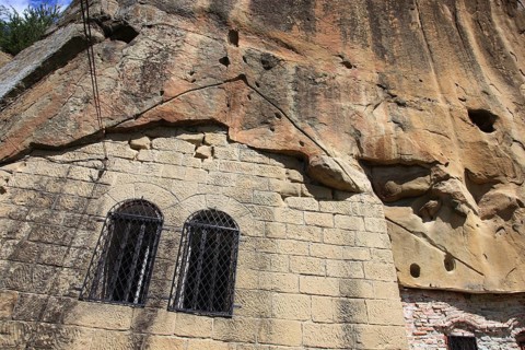 Corbii de Piatra rock monastery, stone ravens carved into a massive, 30-meter high sandstone wall,