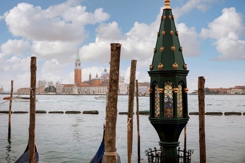 A tranquil view of Venice featuring a scenic waterfront with ornate architecture, wooden poles, and